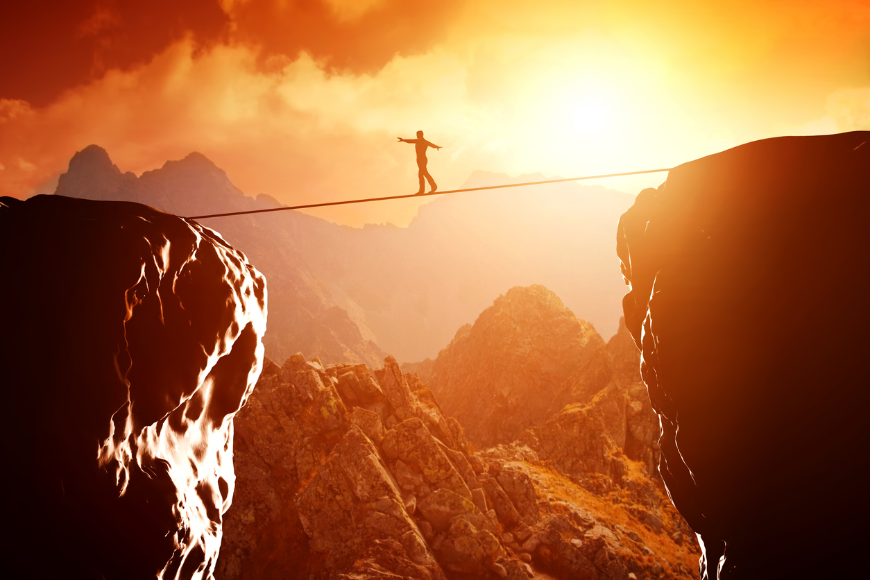 Far off shot of a person on a tightrope between two rocks